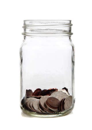 A glass jar full of coins on a white backgroundの写真素材