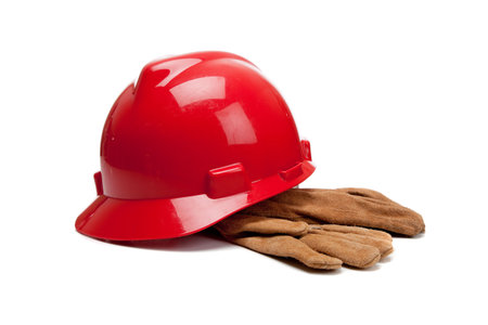 A red hard hat and leather work gloves on a white backgroundの写真素材