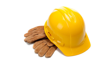 A yellow hard hat and leather work gloves on a white background