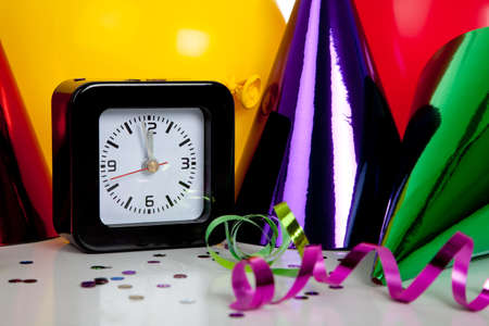 New Year's eve decorations including black clock set to midnight and party hats, streamers, confetti and balloonsの写真素材