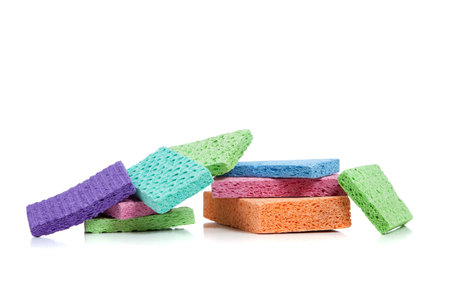 A stack of multi-colored sponges including orange, pink, blue, green and purple on a white backgroundの写真素材