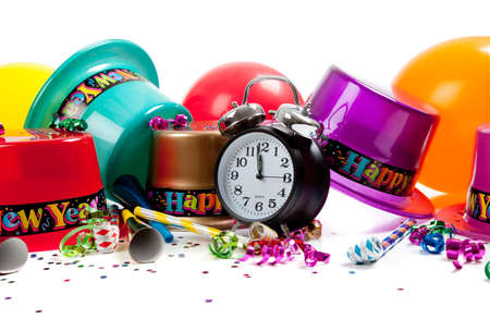 New Year's hats, noise makers, streamers, balloons, confetti and a black clock on a white backgroundの写真素材