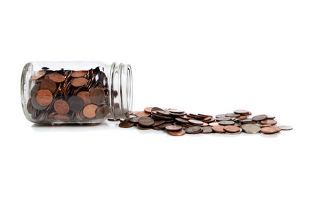 A spilt jar of change including dimes, pennies, quarters and dimes in a white background