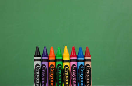 Multicolored crayons in front of a green chalboard backgroundの写真素材