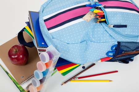 Blue backpack full of supplies including paints, pencils, notebooks, text books, scissors, folders...