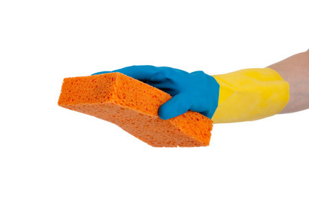 A blue and yellow rubber gloved hand holding an orange sponge on a white background with copy space
