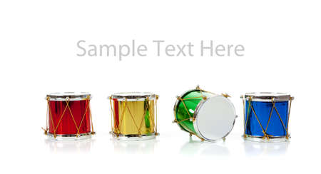 Assorted colored miniature Christmas drums including red, gold, green and blue on  a white background with copy spaceの写真素材