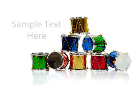 Assorted colored miniature Christmas drums including red, gold, green and blue on  a white background with copy spaceの写真素材