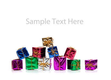 Assorted colored miniature Christmas presents including purple, red, gold, green and blue on  a...