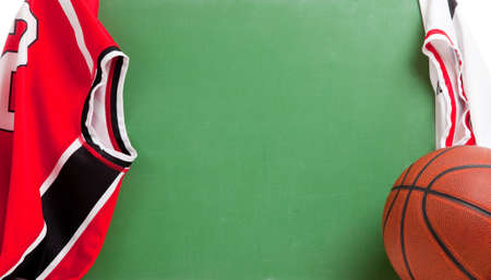 A basketball coach's blank green chalkboard with a basketball and jerseysの写真素材