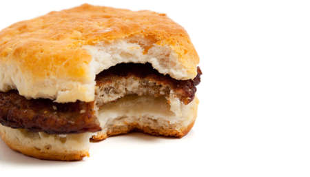 A sausage biscuit with a bite out on a white background with copy spaceの写真素材