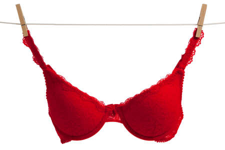 A red lace bra haning on a clothes line with a white background with copy spaceの写真素材