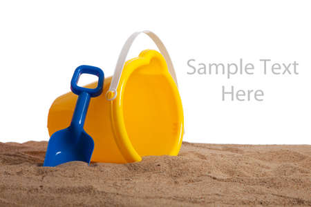 An yellow bucket and blue shovel on a sandy beach with copy space on a white backgroundの写真素材