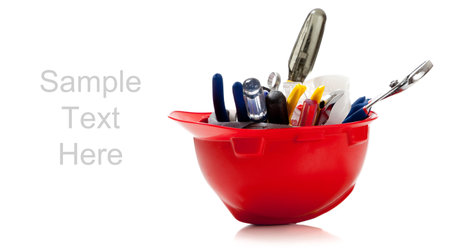 Orange hard hat with screw driver, wrench, pliers on a white background with copy space