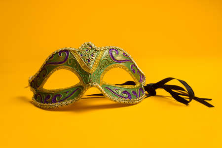 Green, gold, purple mardi gras mask on a bright yellow の写真素材
