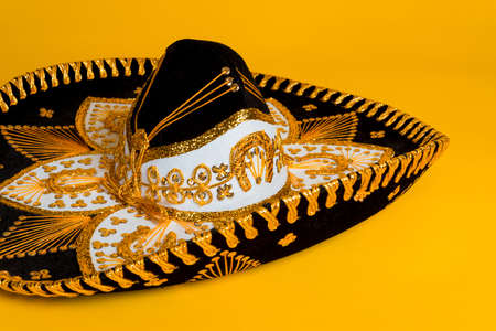 Ornate black, gold and white Mexican sombrero on a bright yellow backgroundの写真素材