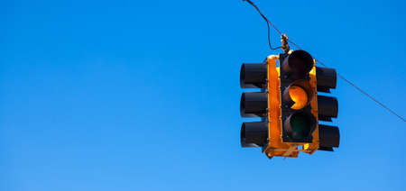 A yellow traffic signal with a sky blue backgroundの写真素材