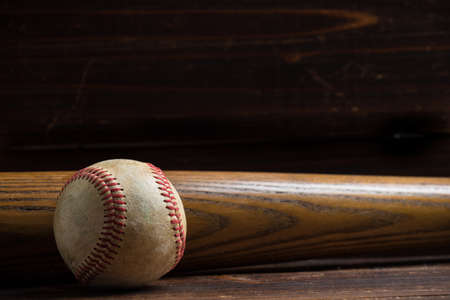 Baseball equipment: wooden bat and ball on a wood plank or bench backgroundの写真素材