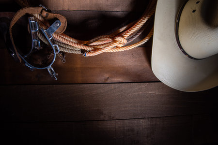 American Cowboy Items incluing a lasso spurs and a traditional straw hat on a wood plank backgroundの写真素材