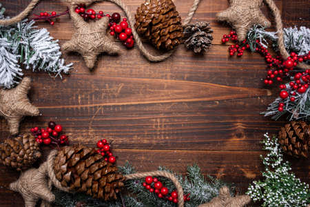 Christmas decorations on a brown wood background with copy space. Pine cones, garland, berries and pine branchesの写真素材