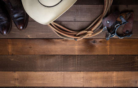 American Cowboy Items incluing a lasso spurs and a traditional straw hat on a wood plank backgroundの写真素材