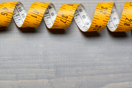 Yellow Tailor measuring tape on wooden table back