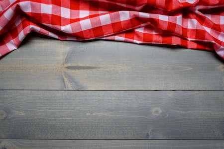 a checked gingham picnic tablecloth on old wooden table top viewの写真素材