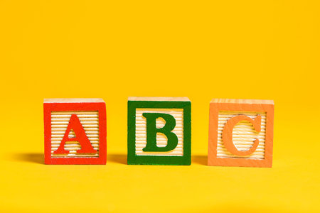 A set of Wooden ABC blocks on bright yellow background