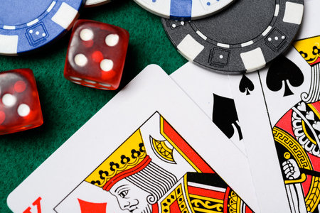 A group of poker chips, dice, playing cards on a green felt backgroud. Gambling, risk theme.