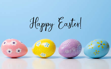 Colorful Easter eggs on blue background with greetingの写真素材