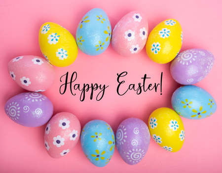 Colorful Easter eggs on pink background with greetingの写真素材