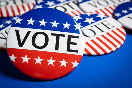 A group of red, white and blue VOTE button on a blue backgroundの写真素材