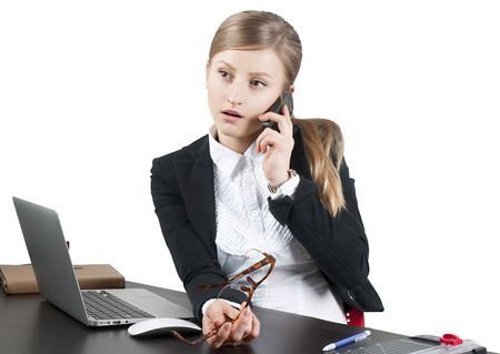 Successful business woman, secretary sitting for table using laptop computer and talking on the phone in officeの写真素材