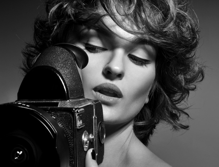 Black and white photo of beautiful sexy woman with photo camera in studioの写真素材