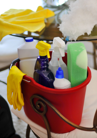 Bucket with cleaning supplies and vacuum cleaner near tableの写真素材