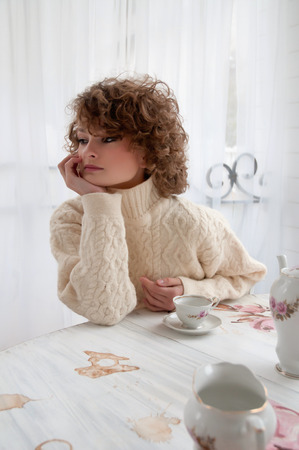 Happy woman in warm sweater with curly hair, smilingの写真素材
