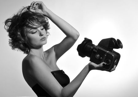 Black and white photo of beautiful sexy woman in black corset with photo camera in studioの写真素材