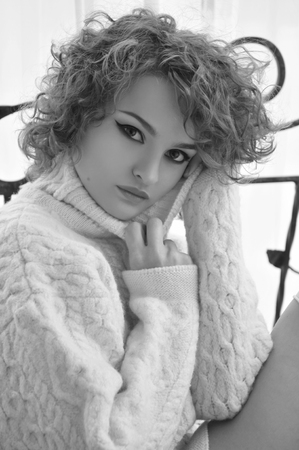 Happy woman in warm sweater with curly hair, smilingの写真素材