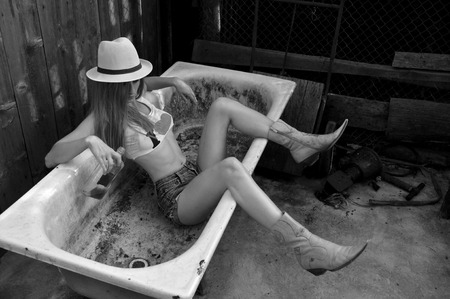 Black and white photo of beautiful, sexy blonde cowgirl in western style in a bathの写真素材