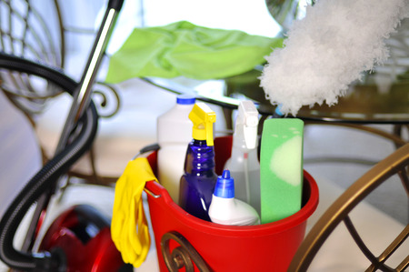 Bucket with cleaning supplies and vacuum cleaner near tableの写真素材