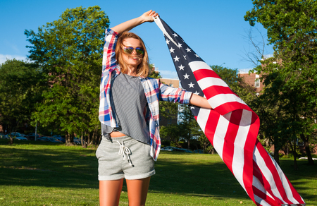 Young happy patriot girl holding the american, united states flagの写真素材