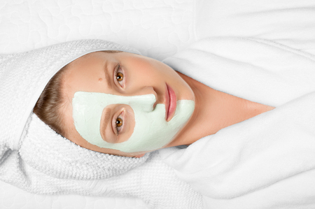 Skin care. Beautiful young woman with cosmetic clay mask on face. Treatment in spa salonの写真素材