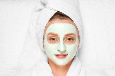Skin care. Beautiful young woman with cosmetic clay mask on face. Treatment in spa salonの写真素材