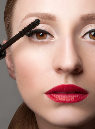 Close up of woman face with mascara brush. Eyes Make-up with Perfect Skinの写真素材