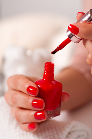 Woman in a nail salon receiving a manicure. Woman's hand with red manicure on nails

の写真素材