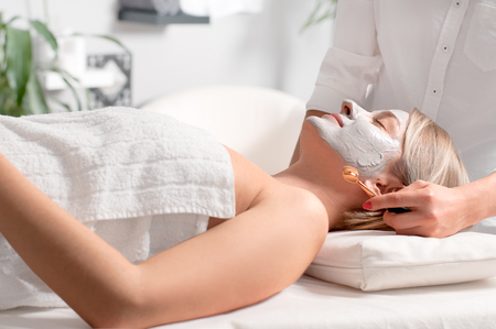 Woman is getting facial clay mask at spa salonの写真素材