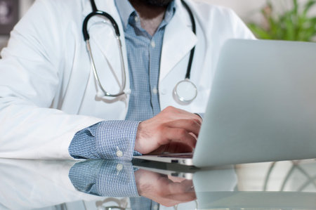 Doctor working on desk with laptop computer in doctors office. Medical, doctor concept
