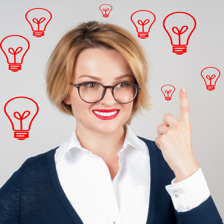 Beautiful business woman has an idea showing finger up on light bulb over her head. Brainstorm. Decision making conceptの写真素材