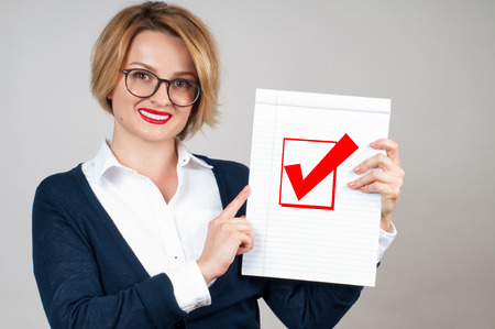 Beautiful business woman holding blank paper with check mark or approved iconの写真素材
