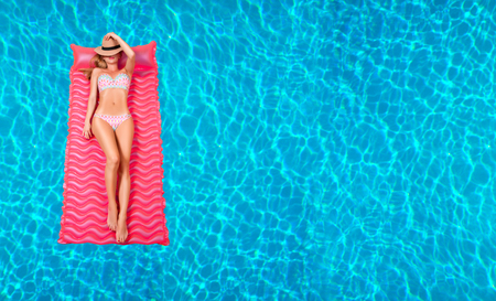 Summer Vacation. Enjoying suntan Woman in bikini on the inflatable mattress in the swimming pool.の写真素材